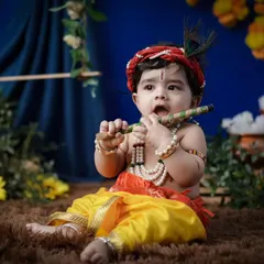 Capturing the innocence of baby Krishna. This portrait shows a younger child dressed in full costume, complete with a peacock feather and flute. The setup is designed to be safe and comfortable for even the smallest babies.