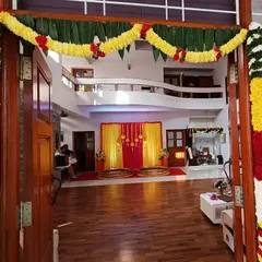 A traditional welcome for a home-based ceremony. The main door is decorated with thick garlands of marigold, mango leaves, and other flowers, setting a festive tone right from the entrance.