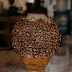 This is my 'Floral Grace' vase, a piece I am incredibly proud of. It is wheel-thrown and then adorned with hundreds of tiny, individually handcrafted clay flowers, with little touches of gold to catch the light.