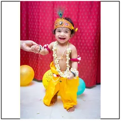 The pure joy of a child during a themed photoshoot. This little one, dressed as Krishna, is sharing a beautiful, genuine smile.