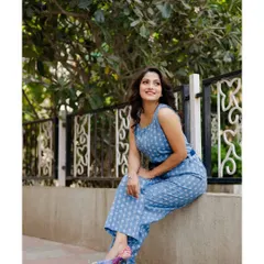 A full-body lifestyle shot for an actress's portfolio. The model is seated casually on a ledge in a stylish blue jumpsuit, creating a confident and modern image.