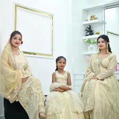 A beautiful family portrait with everyone dressed in our coordinated off-white and gold outfits, including a sharara, an Anarkali, and a kids' lehenga.