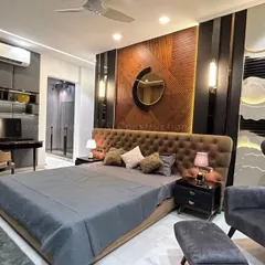 A full view of the master bedroom, highlighting the multi-layered headboard wall that combines wood, textured panels, and ambient lighting. A dedicated study corner is seamlessly integrated into the design.