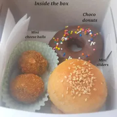 A close-up of our kid-approved party box. It features mini sliders, crispy mini cheese balls, and a delicious choco donut, a combination that is sure to be a super hit with the little guests.