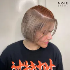 A creative peekaboo hair color. This look features a cool blonde bob with a hidden pop of coppery red underneath, offering a fun and surprising twist.