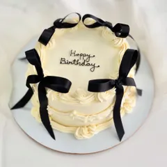 A vintage-style cake with a modern twist, featuring delicate piping and bold black ribbons. This design is a favorite for chic birthday celebrations.