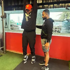 A trainer provides support and guidance as a client works on their pull-up strength.