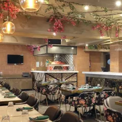 The dining area at Eden Botanic Kitchen, where I handled the general contracting. The space features a wood-fired oven, floral-print chairs, and hanging greenery to create a botanical garden atmosphere.