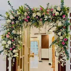 An elegant floral arch can transform your home's entrance for any special occasion. This design uses a beautiful mix of pink and white roses, baby's breath, and fresh greenery to create a warm and inviting welcome for guests.