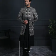 A full-length view of the structured black Achkan, showcasing the beautiful gradient of the silver embroidery. This is a powerful statement piece for any formal occasion.