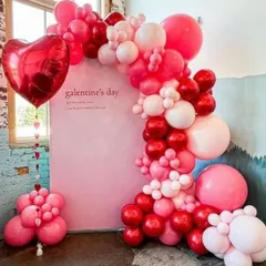 This "Galentine's Day" photo booth features a beautiful balloon arch in shades of pink and red against a simple pink backdrop. The large heart-shaped foil balloon adds a classic romantic touch.