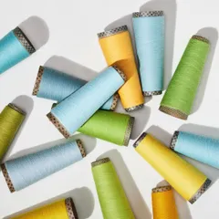 An overhead shot of scattered yarn cones in bright, cheerful colors. This playful composition is full of energy and highlights the vibrant potential of the raw materials.