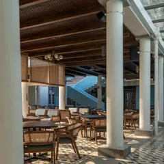 Inside the colonnade, the space is designed for comfortable lounging and dining. The use of Sadharhalli stone for the columns and a skylight separating the new from the old are details that honor the site's legacy.