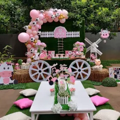 Welcome to our charming pink barnyard. This party theme is perfect for little animal lovers, featuring a complete setup with a custom dessert cart, themed cutouts, a low seating arrangement for kids, and a beautiful balloon arch with cow-print accents.
