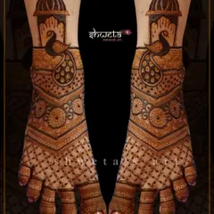A beautiful peacock-themed leg mehendi design. The pattern features a large peacock under a dome, with intricate jaali work covering the rest of the foot for a traditional look.