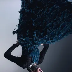 An inverted photograph of a model in a dramatic, textured blue dress. This simple act of flipping the image creates a surreal, gravity-defying effect that is both disorienting and visually captivating.