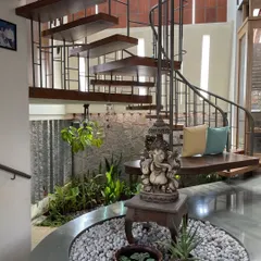 A staircase can be the heart of a home's entrance. This spiral design elegantly ascends from a tranquil indoor garden, combining the structural function of a stair with the serenity of a natural courtyard.