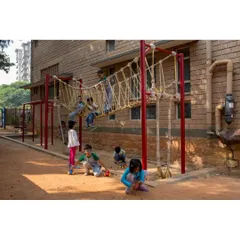 Children playing on a rope bridge in the soft earth play area at Buddhi School. We believe learning happens everywhere, so we incorporate playscapes and interactive elements directly into the school's design.