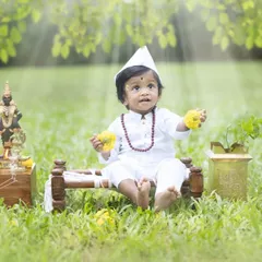This little Varkari is holding flowers as an offering. The details in this themed cultural photoshoot, from the props to the soft lighting, create a truly dreamy and divine image.