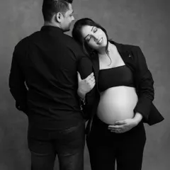 A tender moment captured in classic black and white. The mom-to-be rests her head on her partner's shoulder, creating a feeling of comfort, love, and support.