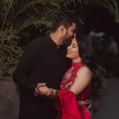 A tender forehead kiss in the evening light. This intimate moment, captured against a backdrop of city lights and foliage, is both romantic and modern.