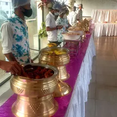 A traditional brass serving pot filled with hot Gulab Jamuns. My staff is shown serving this classic Indian dessert, which is a staple for any celebratory meal.