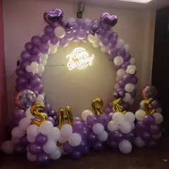 A personalized birthday ring backdrop. We used purple and white balloons, a neon sign, and the birthday person's name in foil letters to create this custom photo booth.