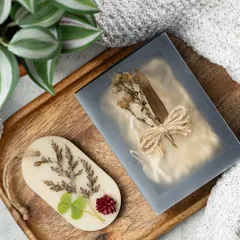 This oval wax tablet features a mix of dried leaves, clover, and a small flower, tied with a rustic twine. They are a great way to freshen up small spaces without a flame.
