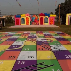 A full view of our giant Snakes and Ladders game set up for an outdoor pre-wedding function. The colorful board and large die make it a visually impressive and highly interactive group activity.