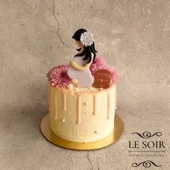 A beautiful cake for a mom-to-be, made by a new mom. This half-kg Vanilla Butterscotch cake has a soft pink drip, fresh flowers, and a serene fondant figurine of an expecting mother.