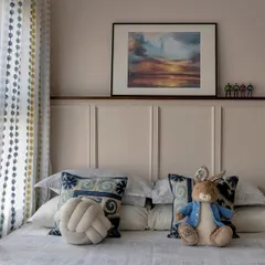 Where dreams take flight. This child's bedroom is styled with a mix of playful and sophisticated elements, including a Peter Rabbit stuffed animal, a knot pillow, and beautiful artwork above the bed.