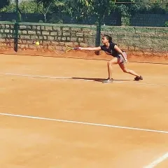 A female competitor lunges for a forehand shot during a UTR tournament, demonstrating focus and determination on the clay court.