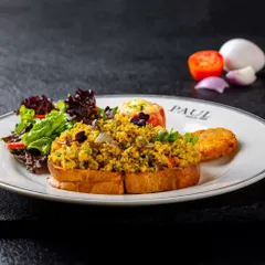 Akuri on toast, a classic Parsi scrambled egg dish, photographed for PAUL India. The dark, slate background makes the colors of the dish and salad pop.