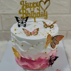 A delicate butterfly cake with a pink ombre wave design. The wafer paper butterflies in shades of pink, gold, and black seem to float around the cake.