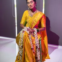 A full-length shot of the bride in her yellow saree, adorned with a long `gajra`, looking serene and beautiful.