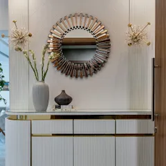 A statement mirror can function as a piece of art. This sunburst-style mirror, paired with starburst sconces and a fluted console, creates a glamorous and welcoming entryway vignette.