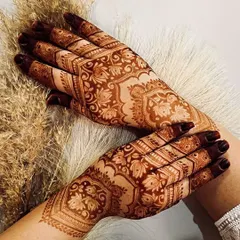 A gorgeous full-hand design for Eid, featuring intricate floral and paisley patterns. The dark stain on the fingertips is a traditional touch that enhances the beauty of the design.
