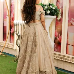 A back view of the champagne gold lehenga, highlighting the stylish blouse design and the flow of the skirt.