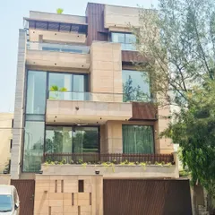 This facade is a thoughtful blend of clean vertical planes and interlocking volumes. The interplay of natural sandstone, glass expanses, and wooden fins creates a rhythmic contrast that is both striking and warm.