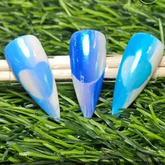 A beautiful example of ombre nail art. This set features a smooth transition from white to different shades of blue, creating a dreamy, cloud-like effect on stiletto nails.
