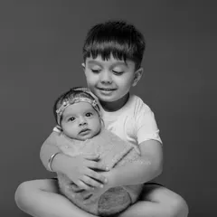 A tender moment as a big brother gently holds his newborn sibling. We specialize in capturing the delicate interactions between children.