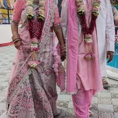 I provide coordinated outfits for the bride and groom. This couple is wearing a matching pink lehenga and kurta set for their wedding ceremony, creating a beautiful, unified look.