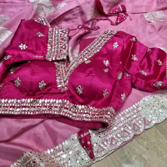 This vibrant pink blouse is brought to life with detailed mirror work and a matching gota patti border on the saree. The puff sleeves add a touch of traditional charm to this festive ensemble.