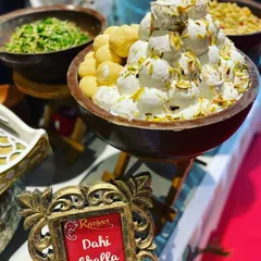 A large bowl of Dahi Bhalla Chaat, generously garnished with nuts. Our chaat counters are always a highlight, offering authentic and refreshing flavors.