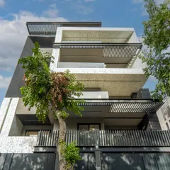 This facade design showcases sustainability and modern aesthetics. Key features include energy efficiency, durable materials like aluminum perforated jali and bricks, and a design that promotes natural ventilation for low maintenance.