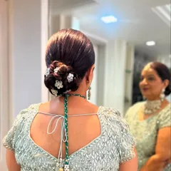 A classic low bun for the mother of the bride, adorned with delicate white floral pins. This timeless hairstyle is perfect for ensuring elegance and comfort throughout the event.