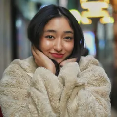 A sweet and happy close up portrait. Her hands framing her face and the colorful lights in the background make this a very charming and engaging night shot.