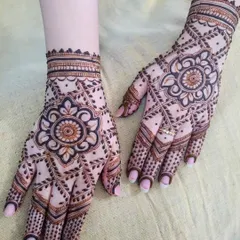 A lovely Eid henna design with a central floral mandala. The pattern spreads out across the hand with a net-like design, giving it a delicate and intricate feel.