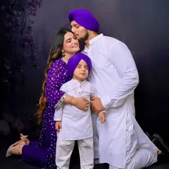 A tender moment as a father kisses his wife's forehead while they hold their young son. This candid family portrait captures the love and affection within the family unit.