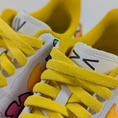 A close-up on the details of the floral customs, including the bright yellow laces and custom tongue tag.